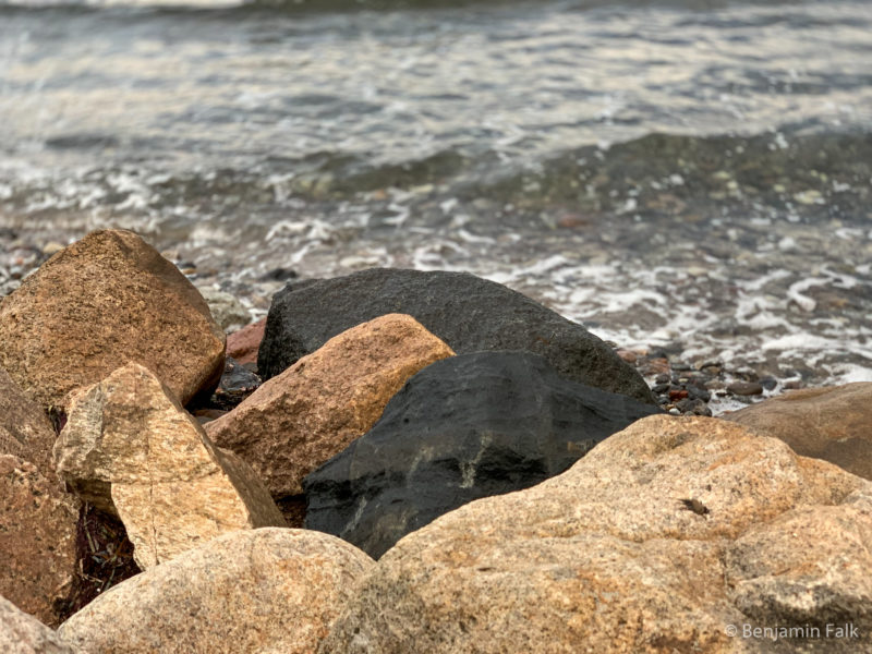 Feuchte Steine vor dem Hintergrund von Wellen und Gischt am Meer.
