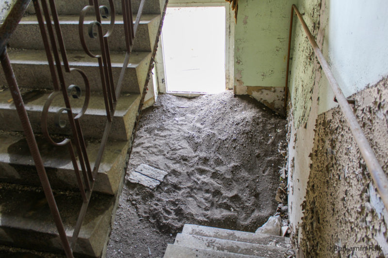 Treppenhaus von oben nach unten Fotografiert mit abblätternder Farbe und einem verschüttetem Grund des Treppenhauses