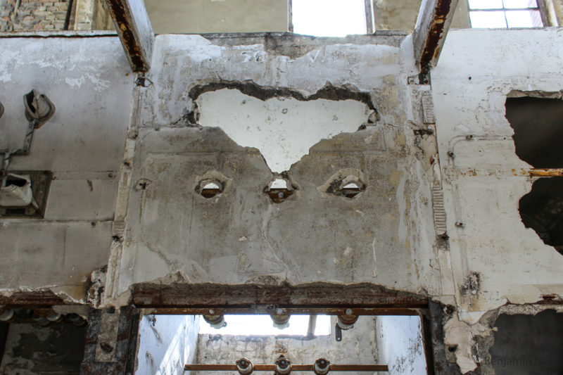 Herzförmiges Loch in einer Betonwand, mit beschädigter Industrie-Elektrik.