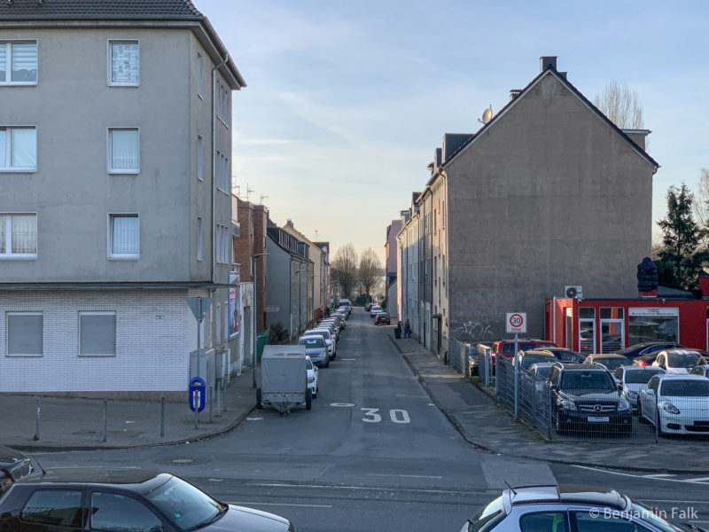 Straßenzug mit geparkten Autos aus einer erhöhten Position heraus fotografiert.