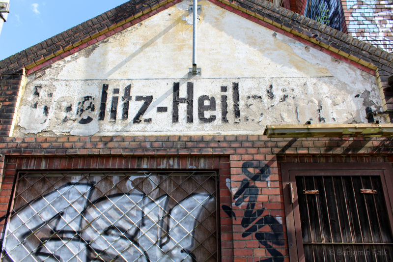 Bahnhofsbeschriftung "Beelitzer Heilstätten" mit abplatzender Farbe.