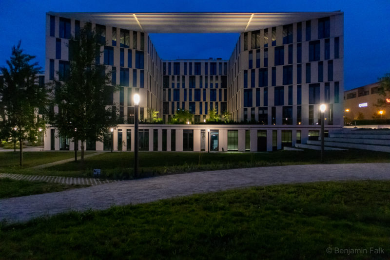 Seitenansicht des Gebäudes der Investionsbank Brandenburg, bei Nacht mit leuchtenden Laternen aufgenommen von der Wiese des angrenzenden Parks.
