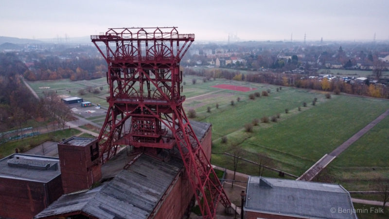 Drohnenfoto am roten Zechenturm (Consolidation, Gelsenkirchen) vorbei über den nebligen Park hinweg zu einem Stadt-Panoroma.