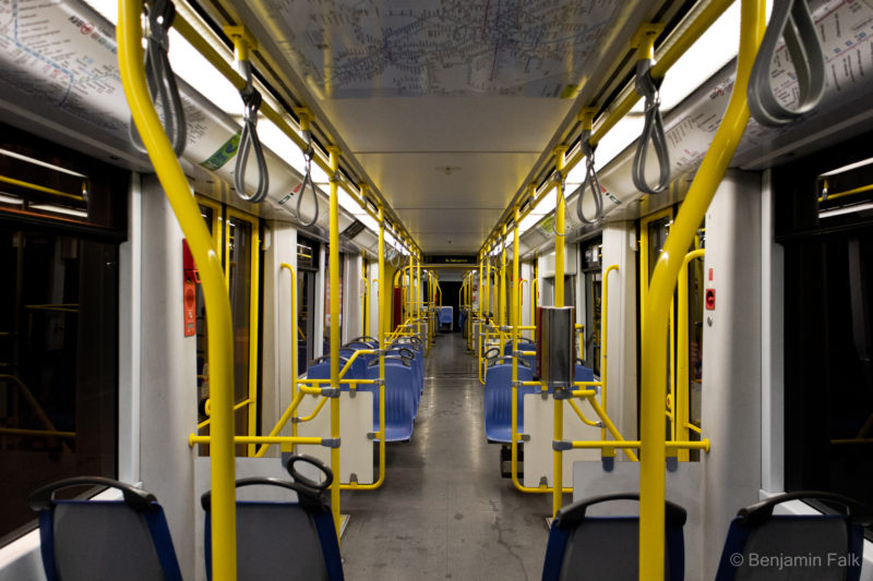 Kölner Straßenbahn bei Nacht, komplett menschenleer, aufgenommen vom hinteren Ende des Wagens mit freier Sichtachse entland des Mittelgangs durch die Haltegriffe zum vorderen Ende des Wagens.